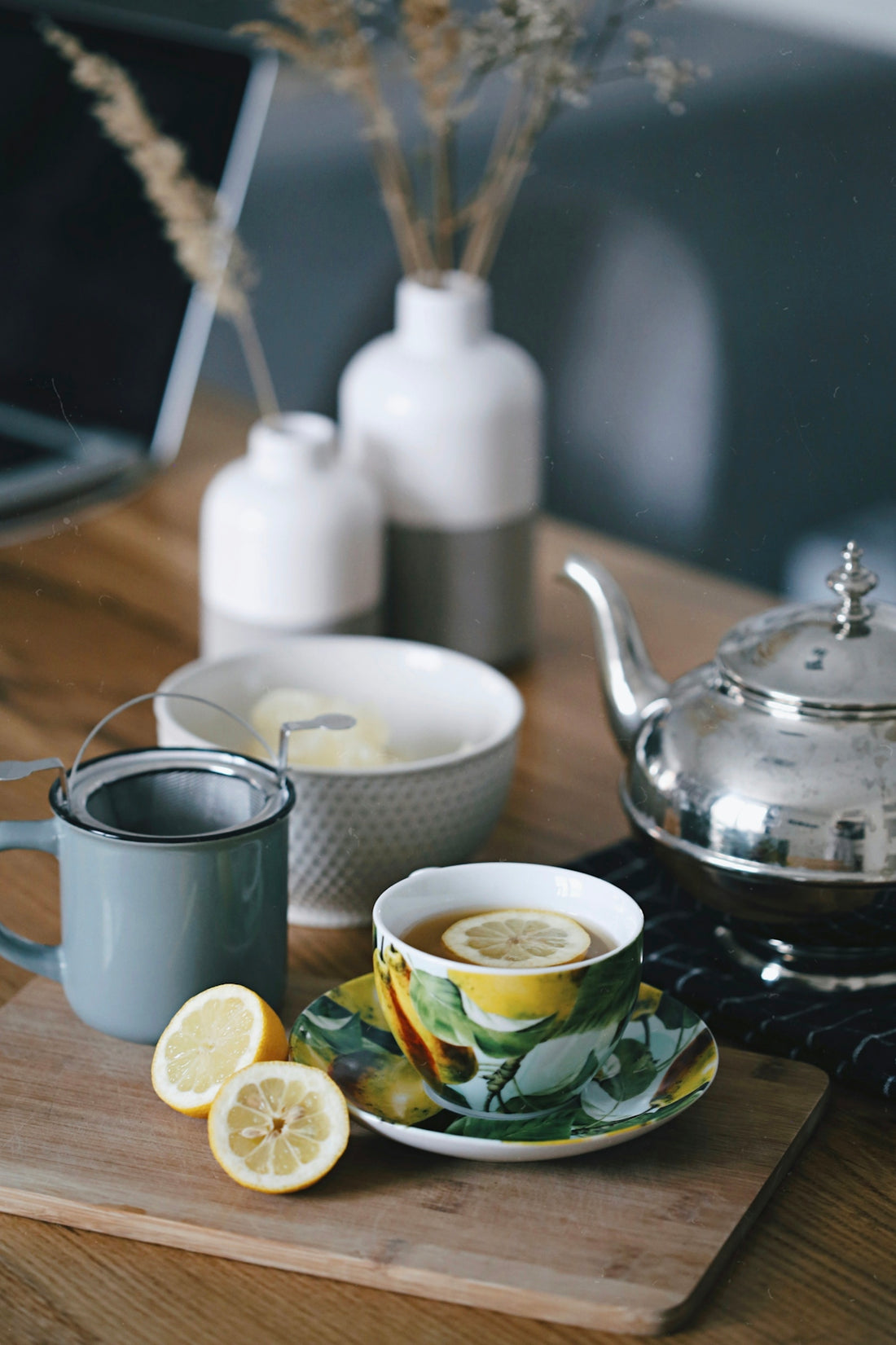 gray teapot beside mug filled with tea and lemon on top of table